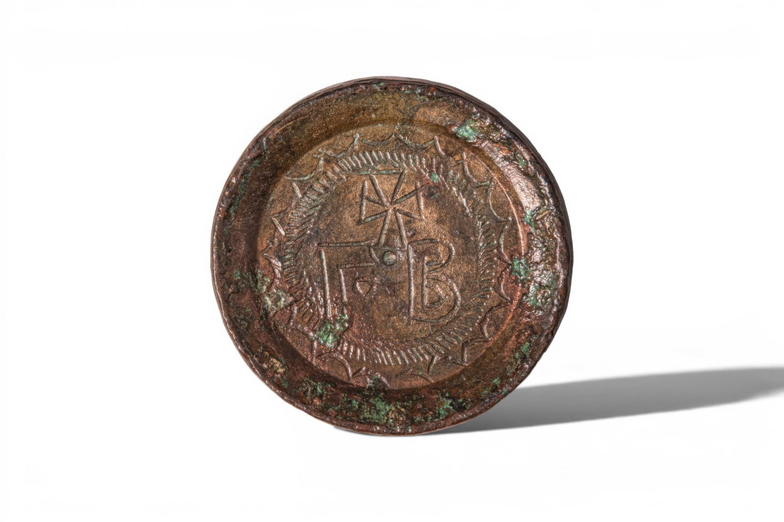 BYZANTINE BRONZE TWO-OUNCE WEIGHT: Ca. AD 700 - 900. A bronze weight of circular form, with a raised rim and a recessed central field engraved with gamma for ounce and beta as a numerical symbol for 2 beneath a cross, within concentric