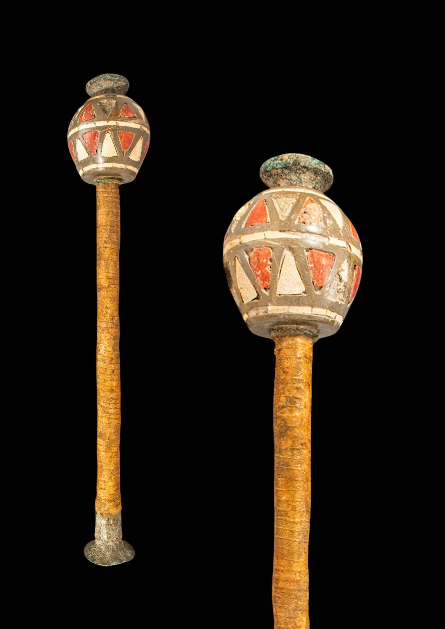 MESOPOTAMIAN BRONZE MACE WITH STONE INLAID HEAD: Ca. 2200 - 1500 BC. A bronze mace with a long cylindrical shaft, a discoid foot, and a globular head with triangular cells inlaid with alternating red and white stone, surmounted by a flat disc knop. 
