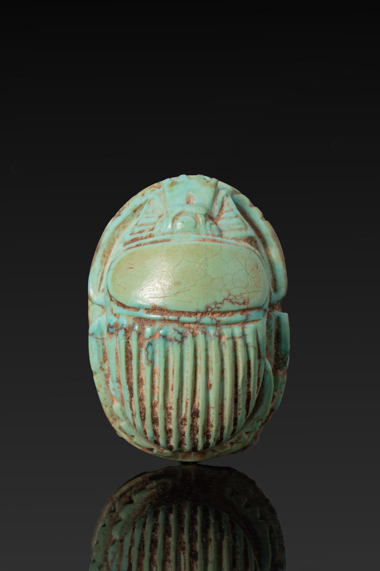 EGYPTIAN GREEN FAIENCE SCARAB: Late Period, Ca. 664 - 332 BC. A green-glazed faience scarab with a domed back and a semi-circular head beneath a serrated clypeus, the prothorax separated from the ribbed wing cases, with the legs cu