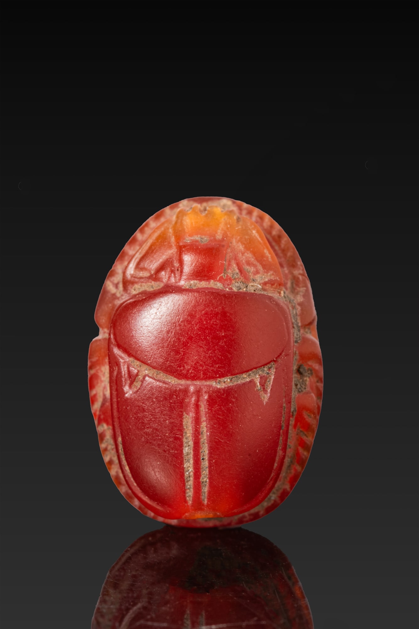 EGYPTIAN CARNELIAN SCARAB: Late Period, Ca. 664 - 332 BC. A carnelian scarab with a domed back and a semi-circular head beneath a serrated clypeus, the prothorax separated from the wing cases, with the legs cut at the sides, pi