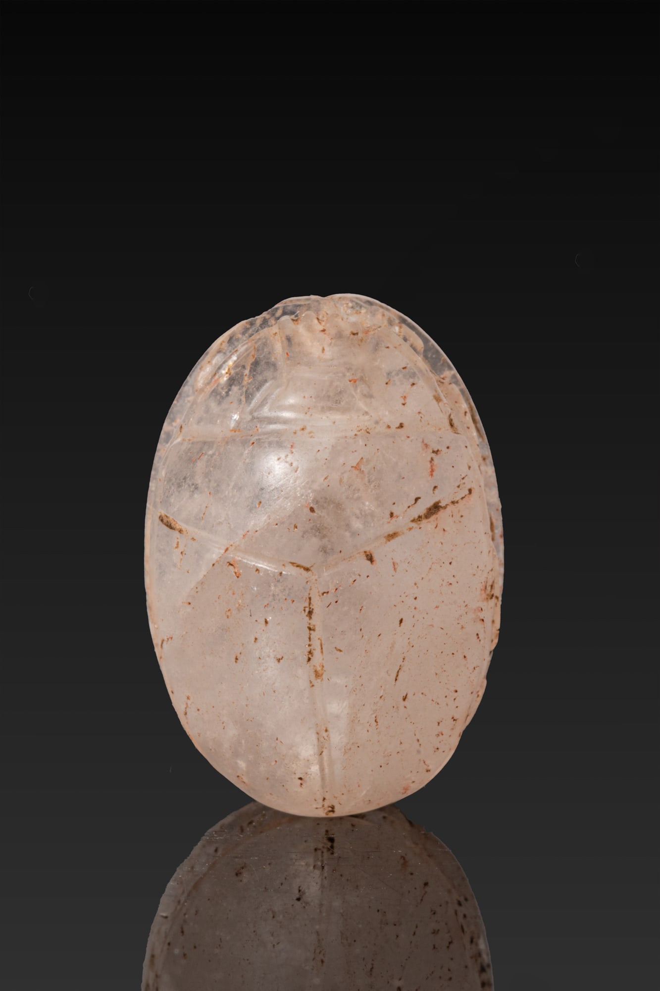 EGYPTIAN QUARTZ SCARAB: Late Period, Ca. 664 - 332 BC. A quartz scarab with a convex back and a semi-circular head beneath a notched clypeus, the pronotum and elytra divided by a single line and the legs tucked beneath the b