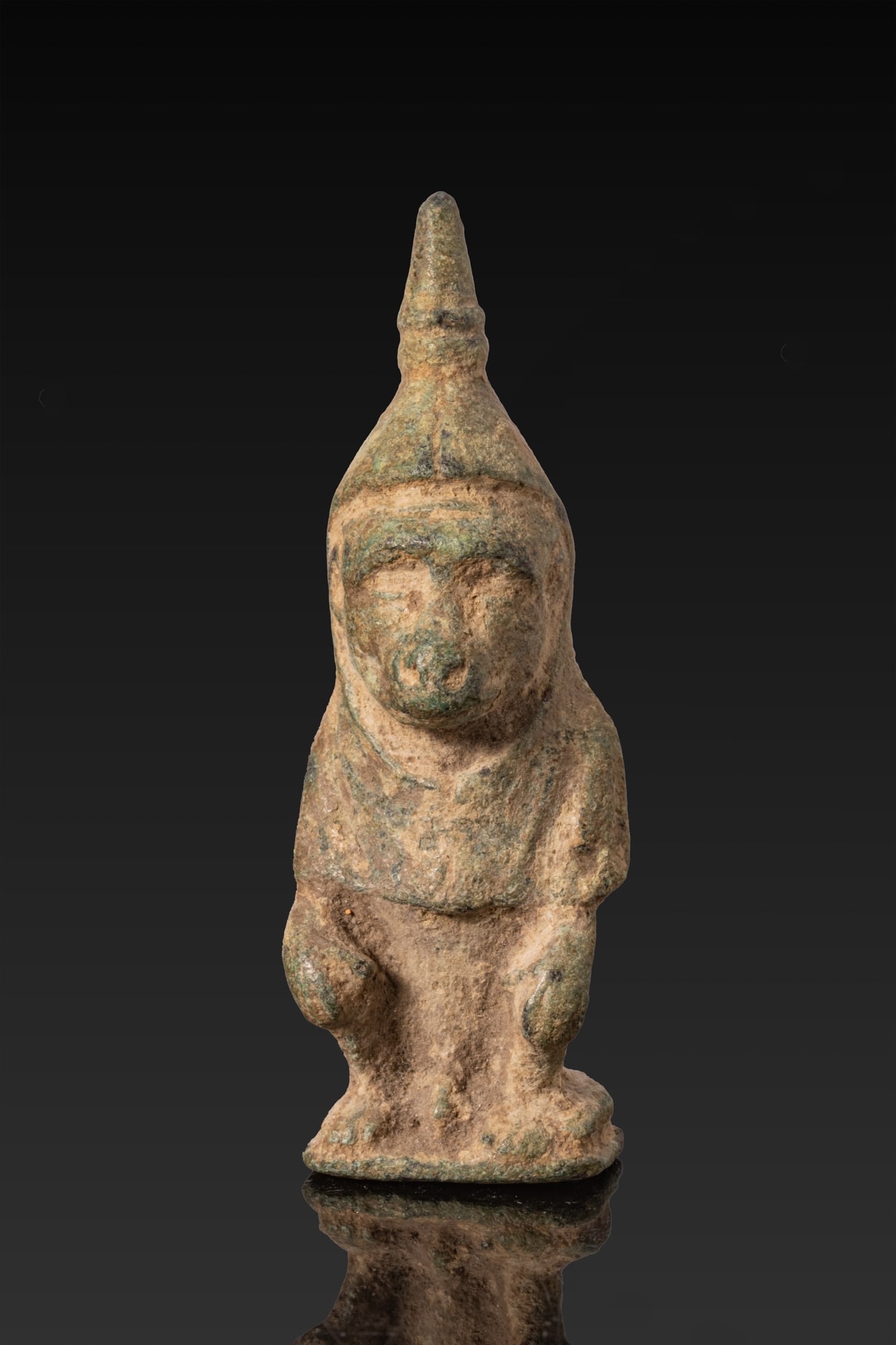 EGYPTIAN BRONZE SEATED BABOON AMULET: Late Period, Ca. 664 - 332 BC. A bronze amulet of a baboon seated on an integral base with its forearms resting on its thighs, the head with a projecting muzzle and recessed eyes, surmounted by a coni