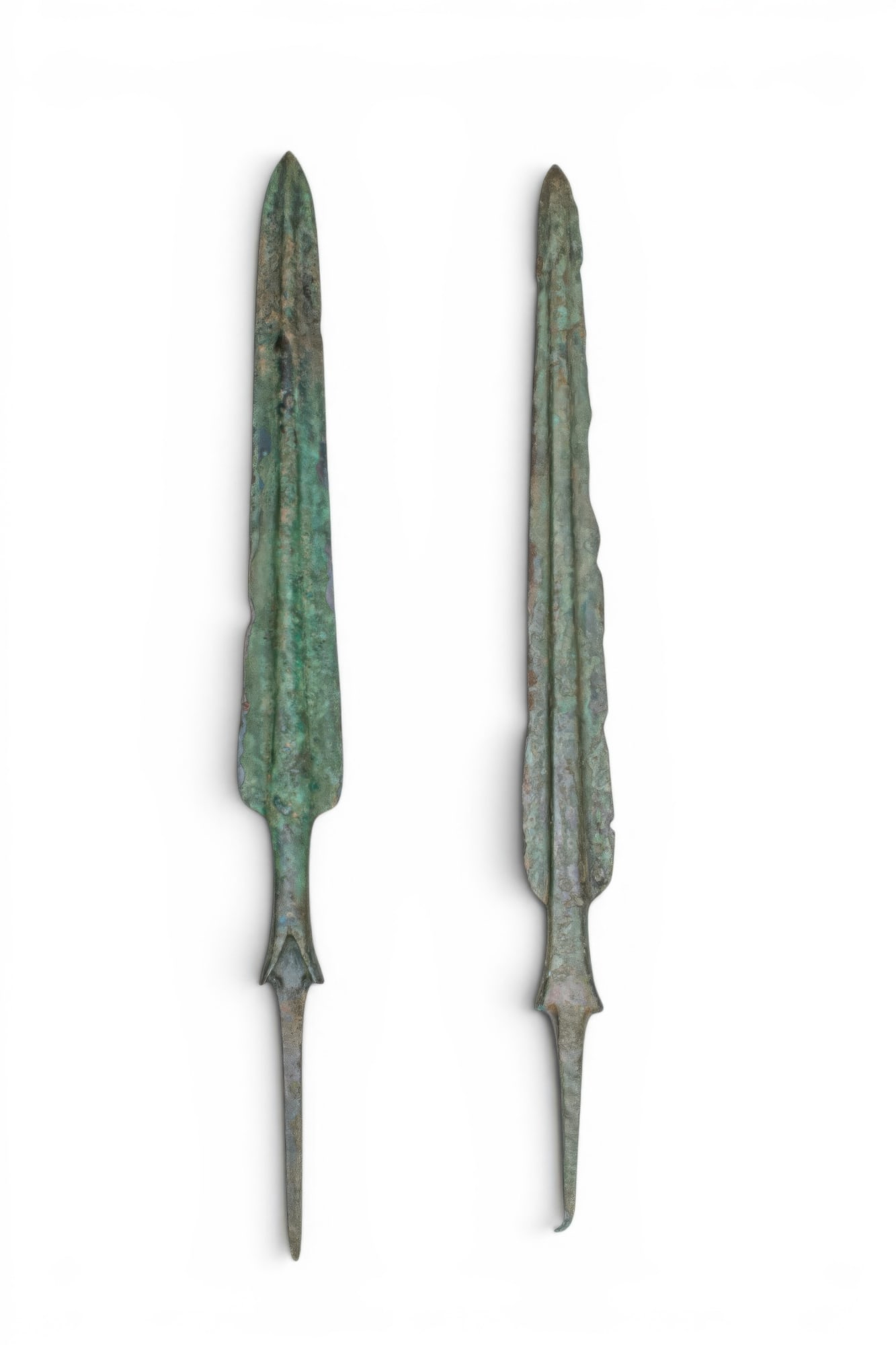 PAIR OF LARGE BRONZE AGE / EARLY GREEK BRONZE SPEARHEADS: Ca. 1200 - 800 BC. A pair of bronze spearheads, each with a leaf-shaped blade with a pronounced midrib, descending to a short tubular shank with a bifurcated terminal, from which extends a long, taper