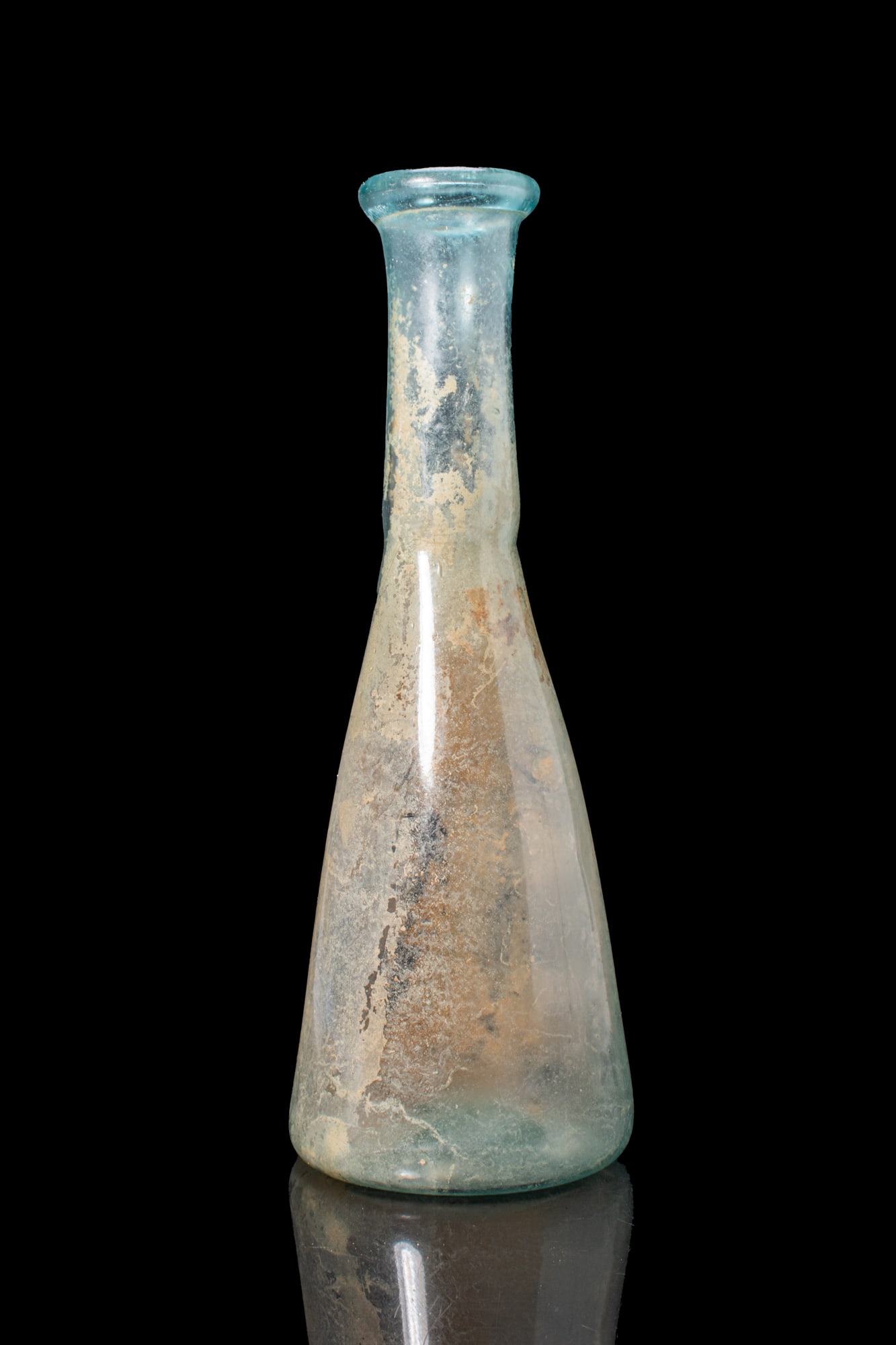 LATE ROMAN GLASS BOTTLE: Ca. AD 300 - 500. A free-blown translucent pale blue-green glass bottle with a tall conical body extending to a cylindrical neck and a folded everted rim. The vessel has a concave base with a pontil s
