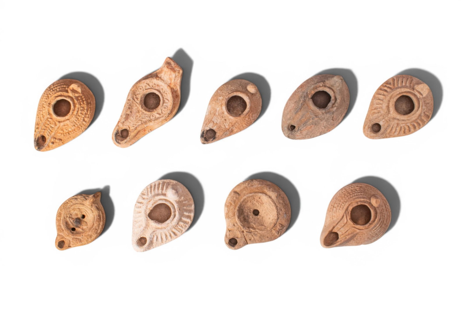 LARGE COLLECTION OF ROMAN AND BYZANTINE TERRACOTTA OIL LAMPS: Ca. AD 1 - 500. A collection of nine mould-made terracotta oil lamps, each of leaf-shaped or circular form with a central filling hole and a rounded nozzle, some with decoration around the perimeter o
