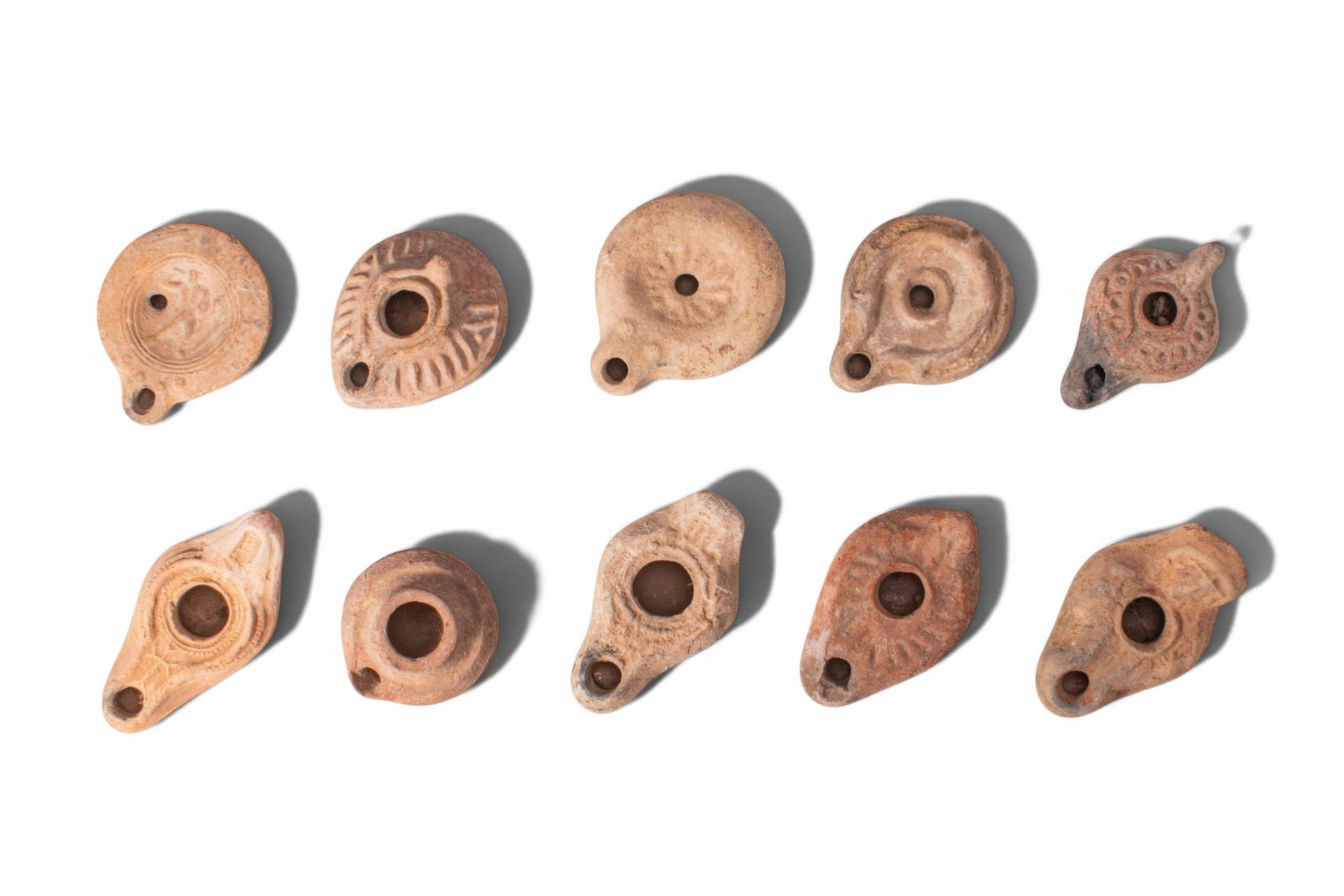 LARGE COLLECTION OF ROMAN AND BYZANTINE TERRACOTTA OIL LAMPS: Ca. AD 1 - 500. A collection of 10 mould-made terracotta oil lamps, each of leaf-shaped or circular form with a central filling hole, a rounded nozzle, and moulded decoration around the perimeter or o