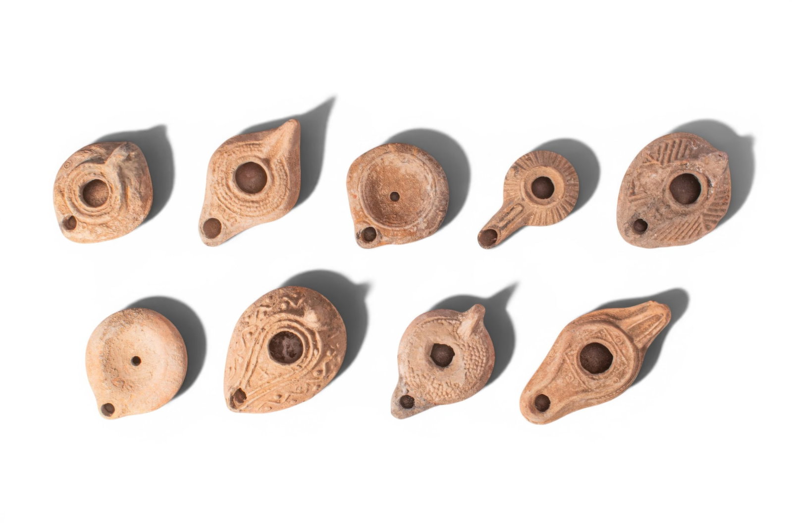 LARGE COLLECTION OF GREEK, ROMAN AND BYZANTINE TERRACOTTA OIL LAMPS: Ca. 200 BC - AD 500. A collection of nine mould-made terracotta oil lamps, each of leaf-shaped or circular form with a central filling hole and a rounded nozzle, some with decoration around the perime