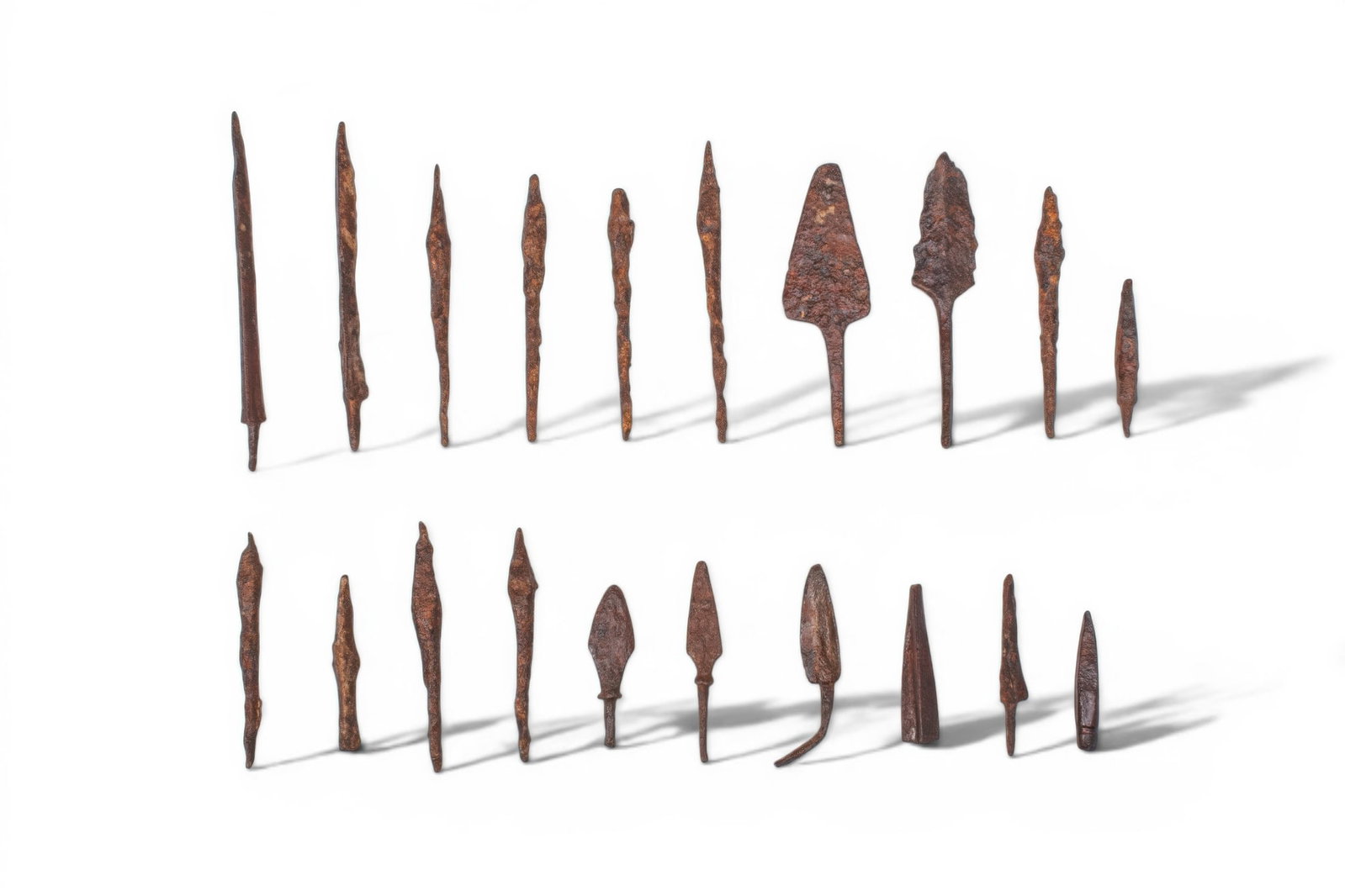 COLLECTION OF ROMAN AND MEDIEVAL IRON ARROWHEADS: Ca. AD 300 - 800. A collection of 20 iron arrowheads, including narrow bodkin types, triangular blades, and leaf-shaped heads, most with an integral tang. Size: 60-125mm x 5-30mm; Weight: 310g Provena