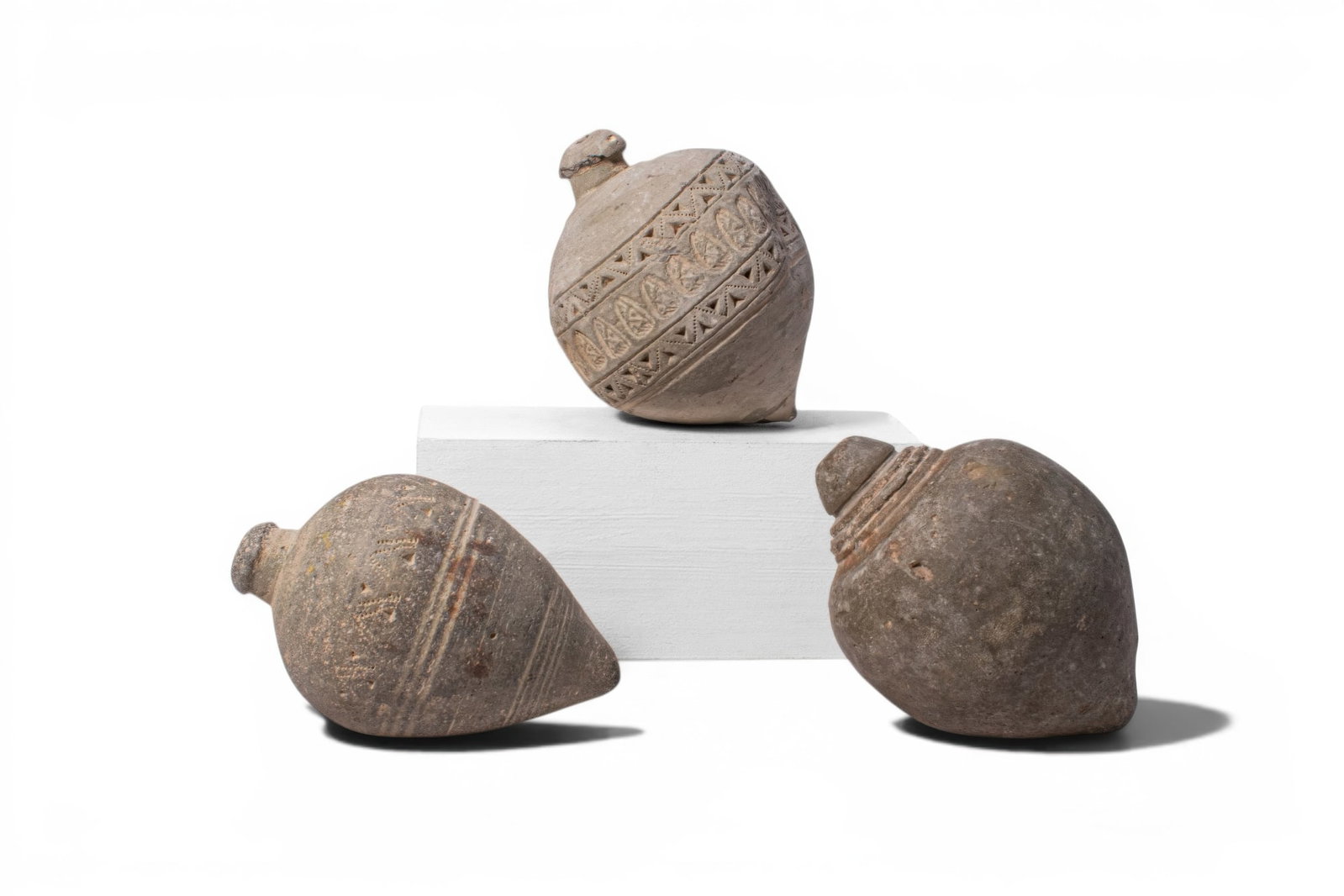 COLLECTION OF BYZANTINE TERRACOTTA GRENADES WITH STAMPED MOTIFS: Ca. AD 1000 - 1200. A collection of three terracotta grenades, each with a rounded body tapering to a pointed tip and a short neck with a domed mouth, including, from top to bottom: one decorated with