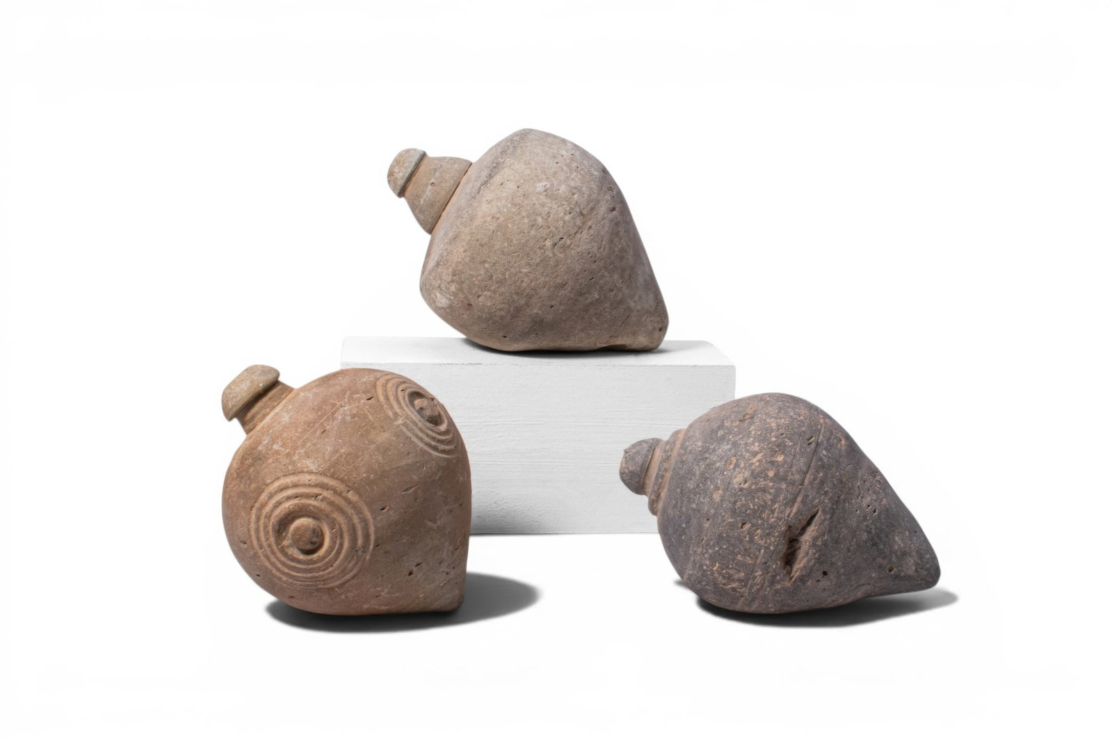 COLLECTION OF BYZANTINE TERRACOTTA GRENADES WITH STAMPED MOTIFS: Ca. AD 1000 - 1200. A collection of three terracotta grenades, each with a spheroconical body and a short cylindrical neck with a domed mouth; two examples plain, the third with stamped concentric rin
