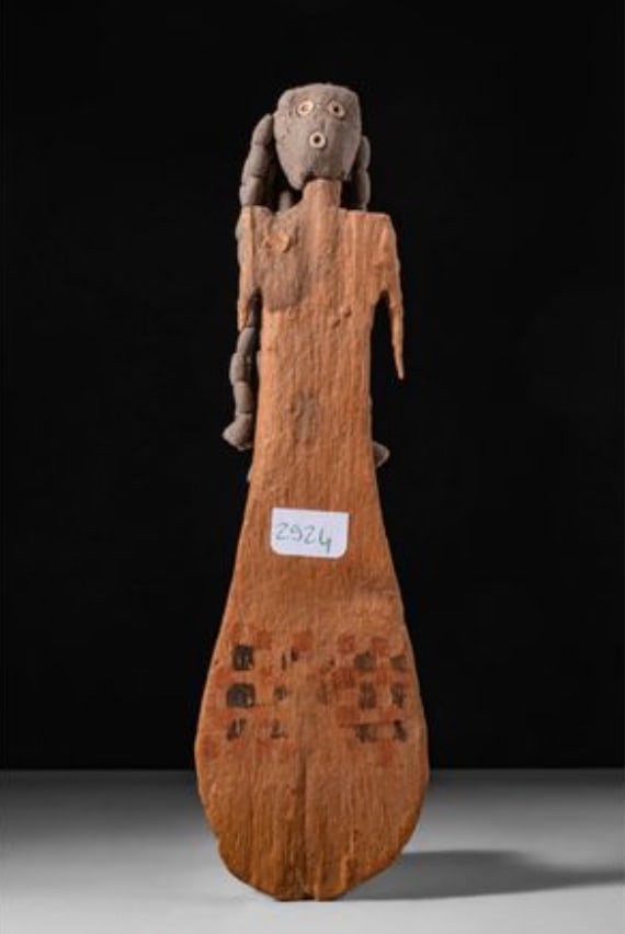 RARE EGYPTIAN WOODEN PADDLE DOLL: 11th-13th Dynasty, Ca. 2130 – 1650 BC. A wooden figurine with a flat, paddle-shaped body tapering at the top and widening towards the rounded base. The lower section is painted with a checkerboard p