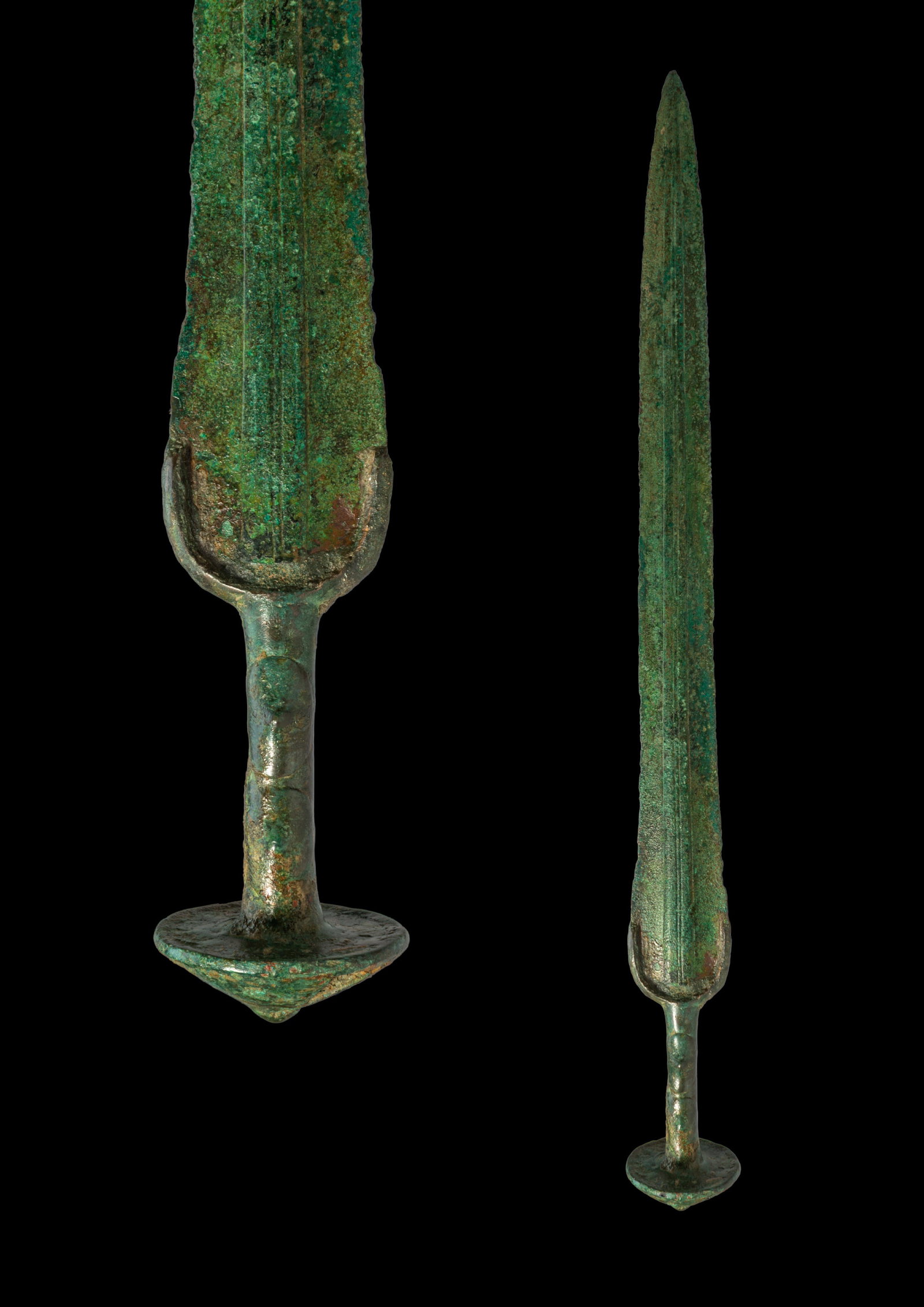 BRONZE AGE / EARLY GREEK PERIOD BRONZE SWORD: Ca. 1200 - 900 BC. A bronze sword with a long tapering blade and a narrow point. A central rib runs along the blade, with fine recessed fullers extending from the shoulder area. The guard is rounded a