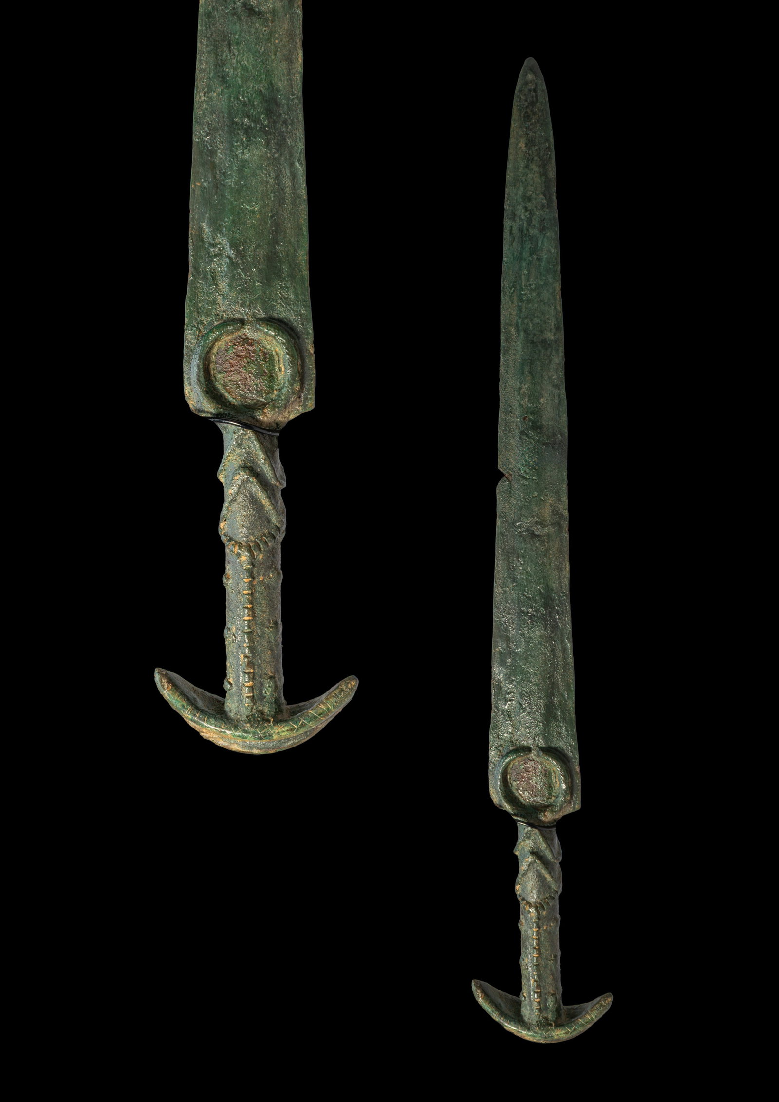 HITTITE BRONZE SWORD WITH CRESCENTIC POMMEL: Ca. 1500 - 1200 BC. A bronze sword with a long tapering blade, a narrow point, and a penannular guard. The cylindrical hilt is decorated with two raised chevrons and rows of raised rectangular bosses,