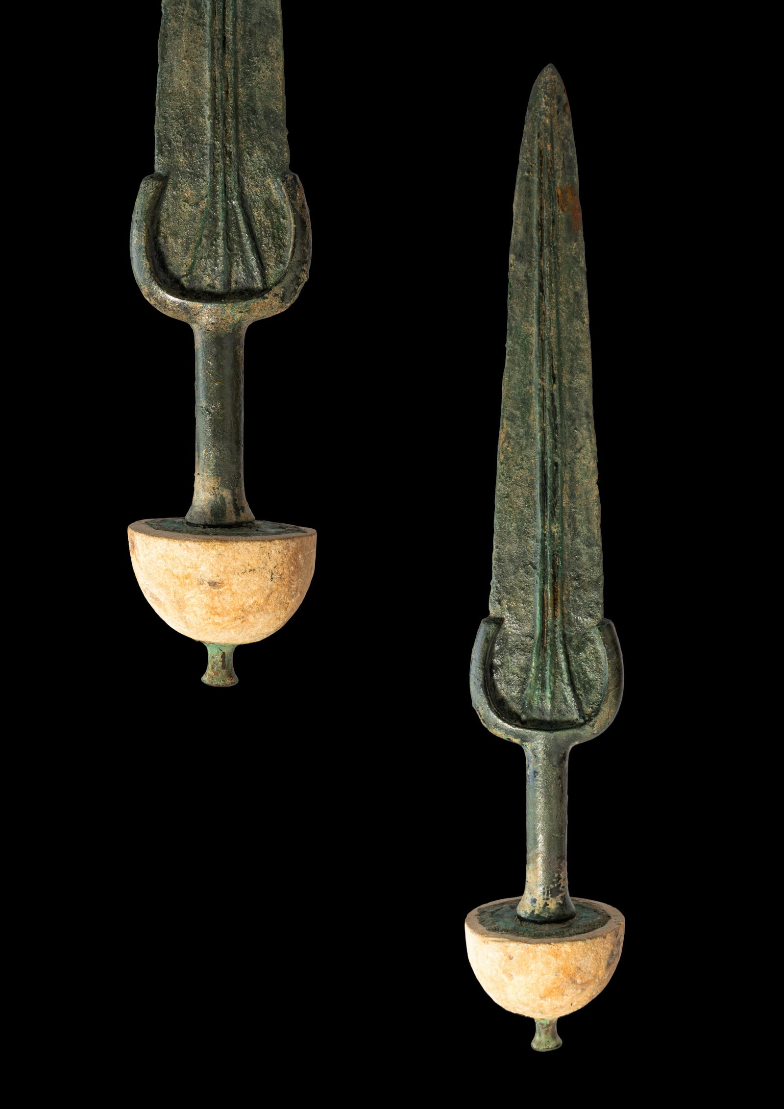 BRONZE AGE / EARLY GREEK PERIOD BRONZE SWORD WITH STONE POMMEL: Ca. 1200 - 900 BC. A bronze sword with a long blade tapering to a narrow point. Three ribs extend along the blade from the shoulders. The arched guard follows the line of the shoulders and continues i