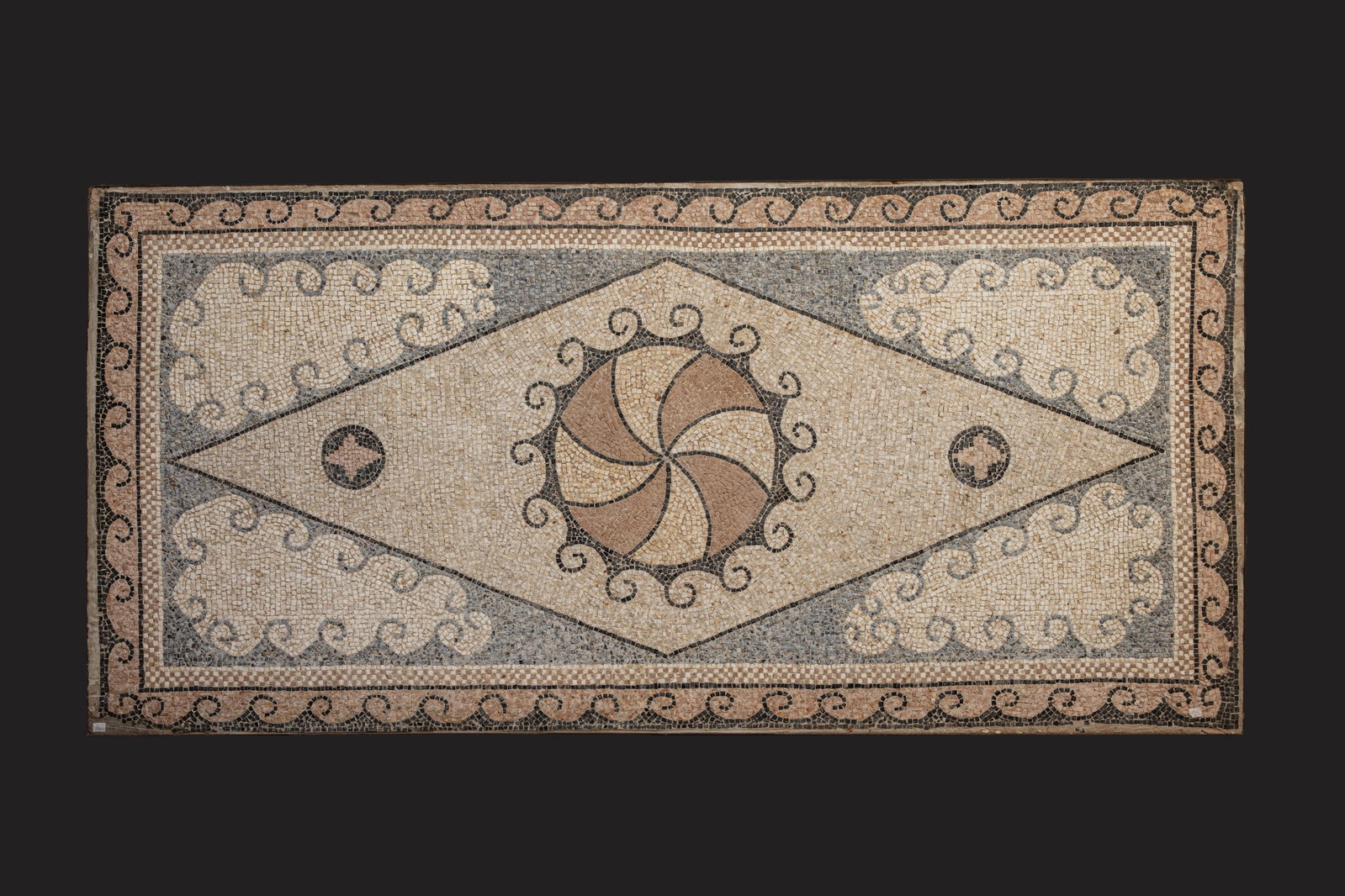 ROMAN POLYCHROME MOSAIC WITH GEOMETRIC MOTIF: Ca. AD 200 - 300 . A rectangular polychrome mosaic panel in *opus tessellatum*, its elongated proportions suggesting an original placement within a corridor or long reception room of a Roman villa. Th