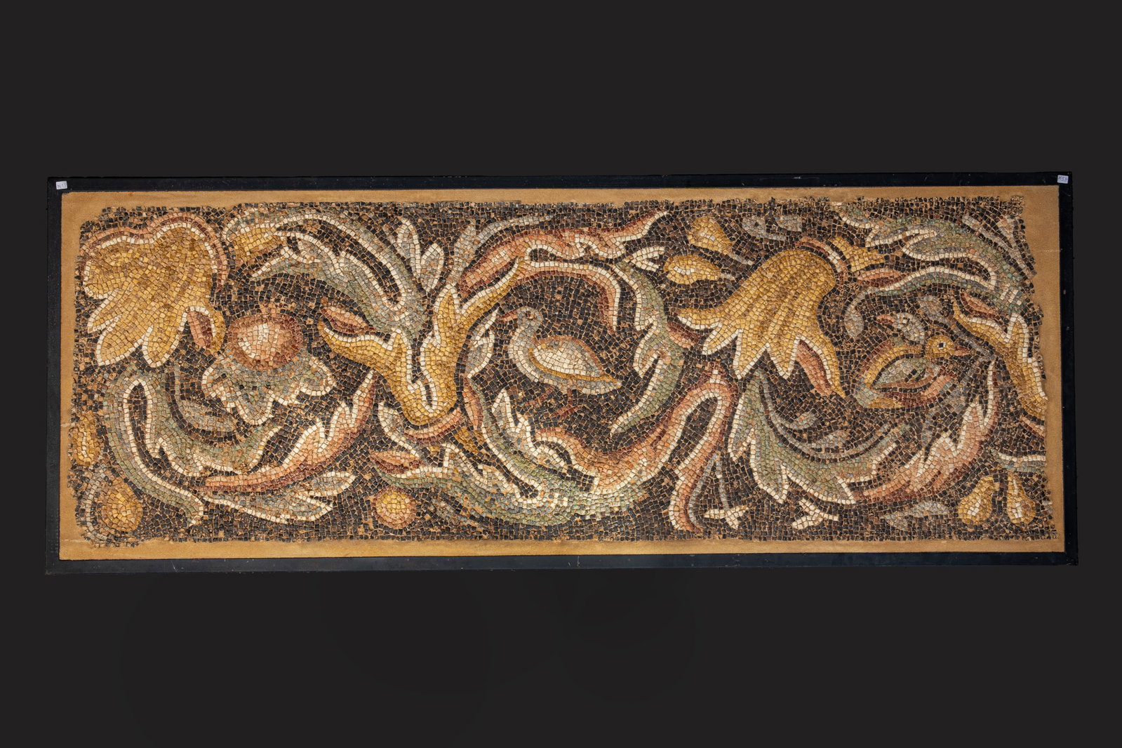 ROMAN POLYCHROME MOSAIC PANEL WITH BIRDS AND ACHANTUS SCROLLS ON A DARK GROUND WITH NILOTIC SCENE: Ca. AD 270 - 320 . A finely constructed polychrome mosaic panel in *opus tessellatum*, centred by a waterfowl shown in profile amid an elaborate arrangement of scrolling achantus, vines, broad leaves,