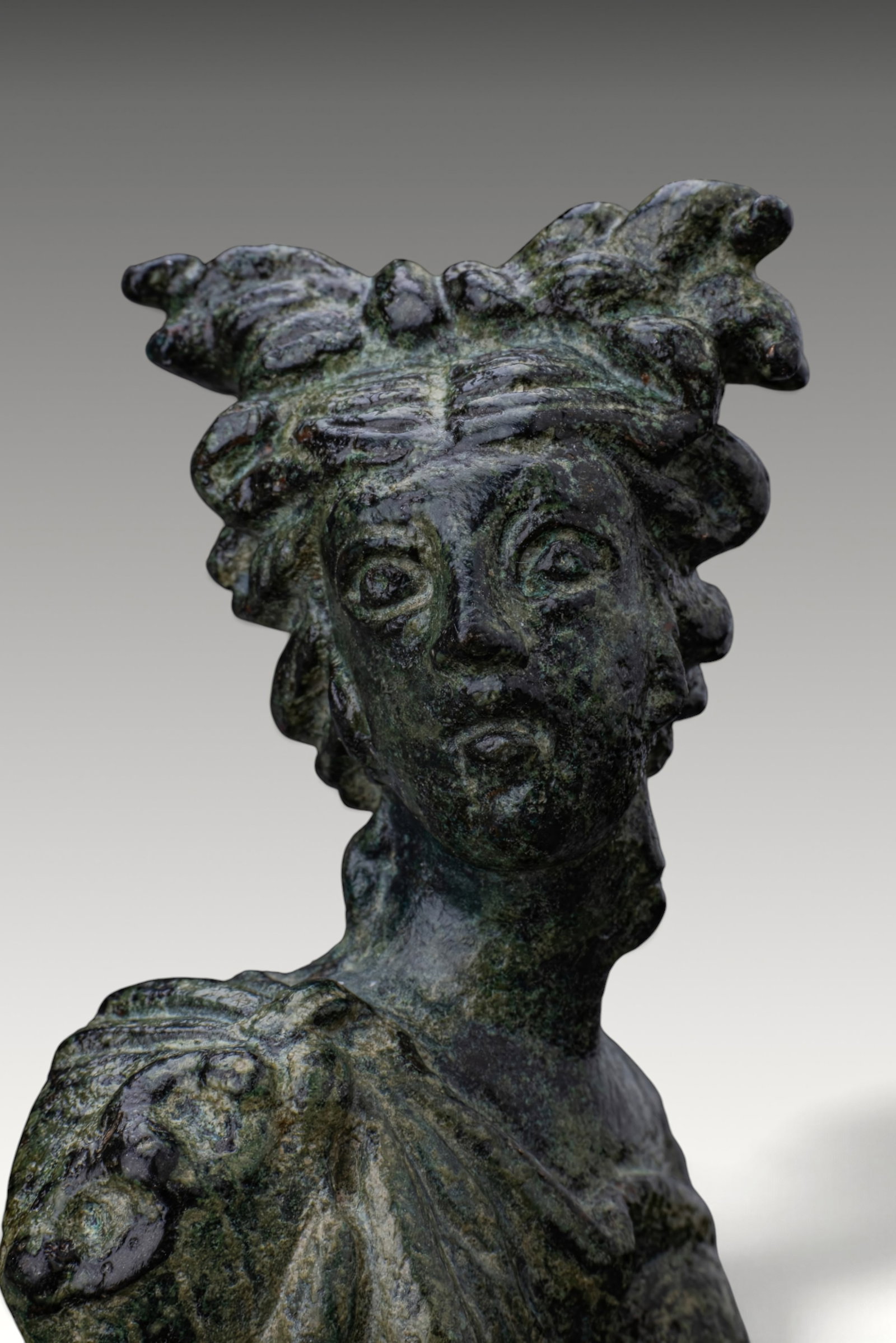 ROMAN BRONZE BUST OF VENUS APPLIQUE: Ca. AD 1 - 300 . A bronze hollow applique in the shape of a bust of Venus, her head turned to her right. The hair is arranged in thick wavy locks and gathered into a high knot. Broad folds of drapery 