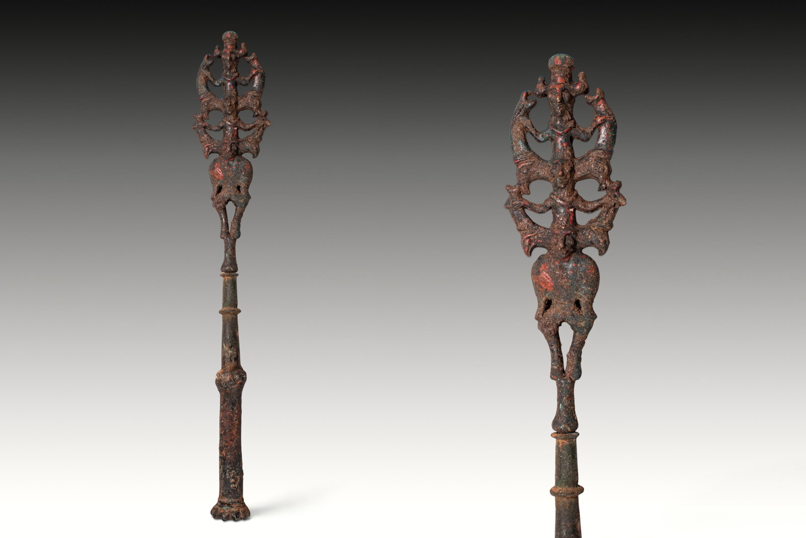 BRONZE AGE BRONZE STANDARD WITH MASTER OF ANIMALS FLANKED BY RAMPANT ANIMALS: Ca. 1200 - 800 BC. A bronze standard with a long cylindrical shaft divided by raised collars and tapering upward to an openwork janiform finial arranged vertically with three human figures, one above 