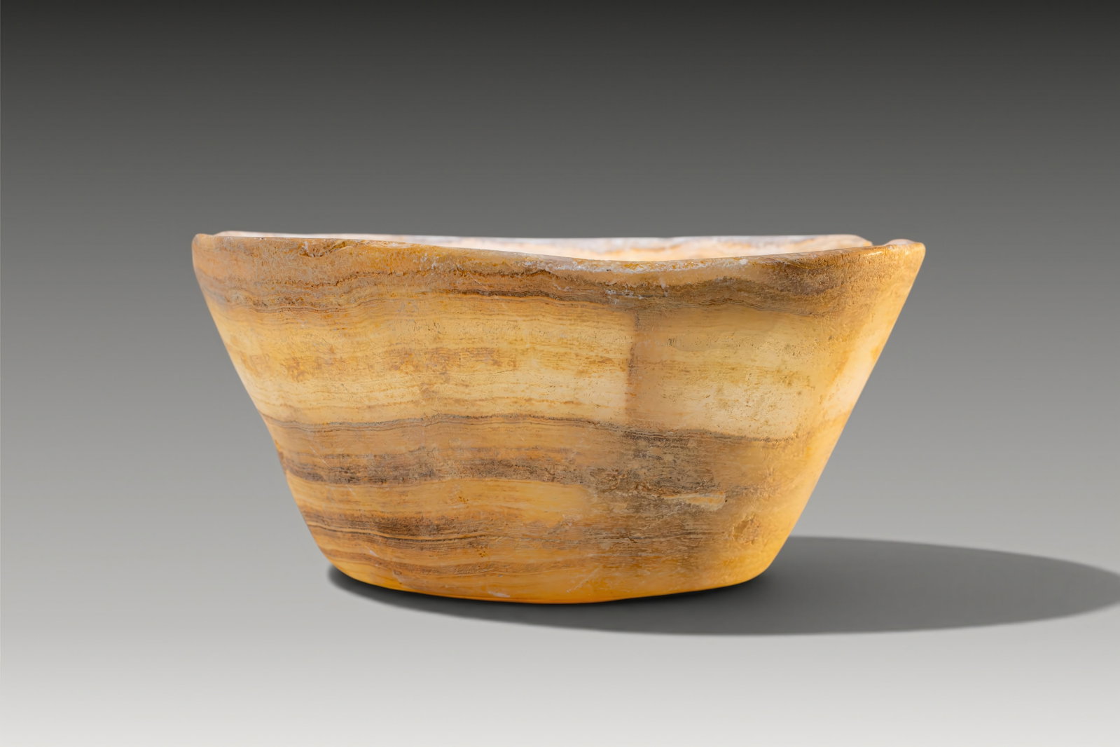 RARE EGYPTIAN VEINED ALABASTER BOWL: Old Kingdom, Ca. 2640 - 2200 BC. An alabaster bowl with a truncated conical body and broad open mouth. The sides flare evenly from the flat base to a plain rounded rim. Size: 80mm x 185mm; Weight: 1.3