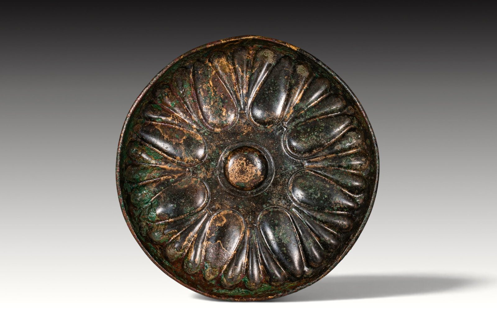 SUPERB GREEK PERIOD BRONZE MESOMPHALOS BOWL: Ca. 500 - 300 BC. A bronze mesomphalos bowl with a shallow rounded body, plain rim, and central raised boss encircled by radiating lotus petals. Size: 195mm x 30mm; Weight: 280g Provenance: Private UK