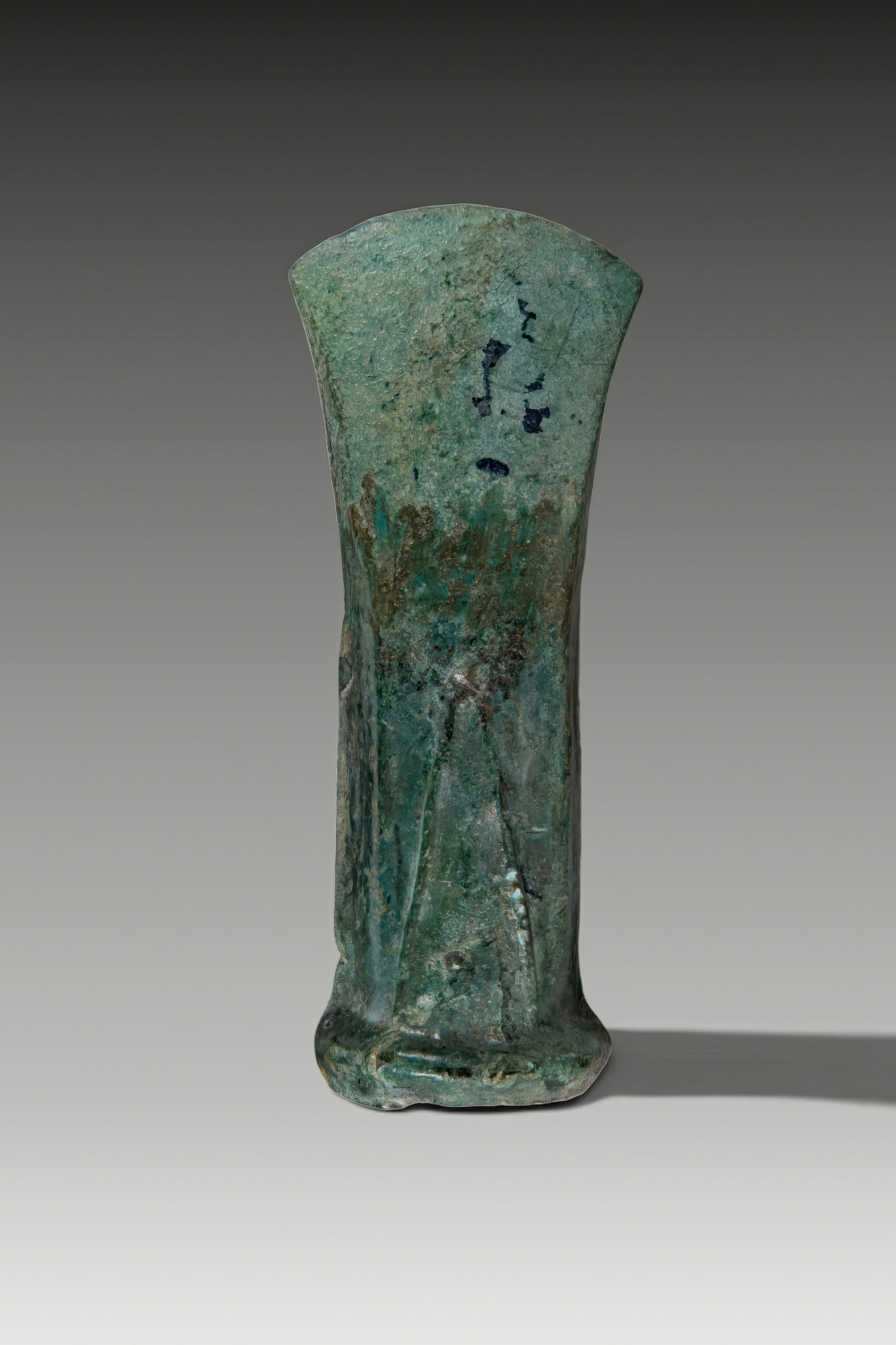 CELTIC BRONZE SOCKETED AXE HEAD WITH GEOMETRIC DECORATION: Ca. 900 - 700 BC. A bronze socketed axe head with a narrow body expanding to a broad curved cutting edge. The rounded socket mouth has a thickened rim, and the cheeks are decorated with raised