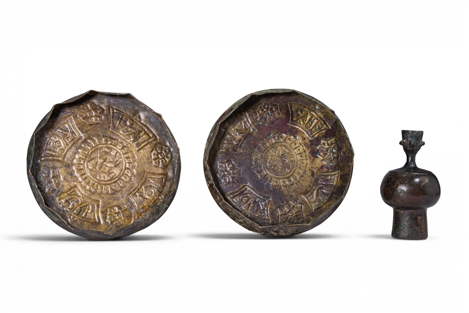 COLLECTION OF SELJUK COPPER ALLOY AND BRONZE VESSELS: Ca. AD 1000 - 1200. A collection of three vessels, including, from left to right: two shallow copper alloy dishes, each decorated with a central medallion and radiating panels of geometric ornament; a