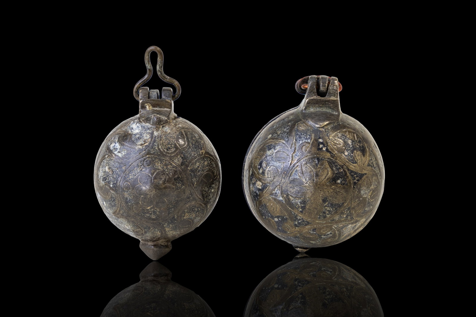PAIR OF SELJUK SILVER-INLAID PORTABLE INKWELLS: Ca. AD 1000 - 1200. A pair of silver-inlaid bronze portable inkwells, each with a hinged spherical body divided into two hemispherical compartments. One half encloses a recessed ink reservoir with a c