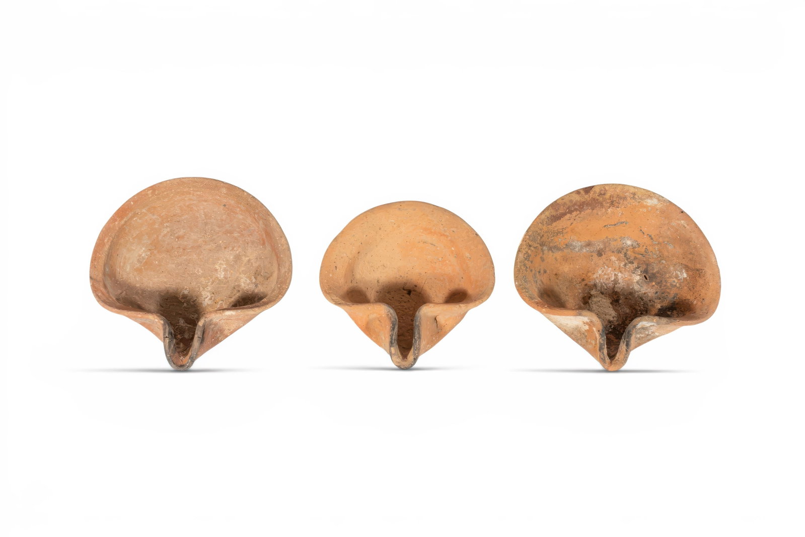 COLLECTION OF IRON AGE HOLY LAND TERRACOTTA OIL LAMPS: Ca. 800 - 500 BC. A collection of three terracotta oil lamps, each of Vessberg Type 1, with a shallow rounded body, broad open basin, and pinched nozzle. The rims are folded inward to frame the fillin