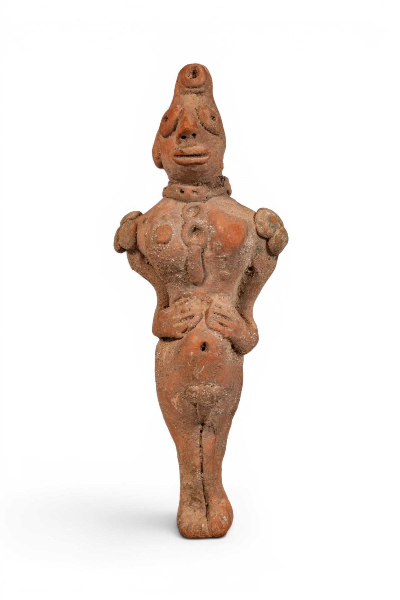 INDUS VALLEY MOHENJO-DARO TERRACOTTA IDOL: Ca. 2500 - 1800 BC. A terracotta standing male idol with an elongated body and applied ornaments across the torso. The head has a high headdress, large applied eyes, a prominent nose, and a broad mout