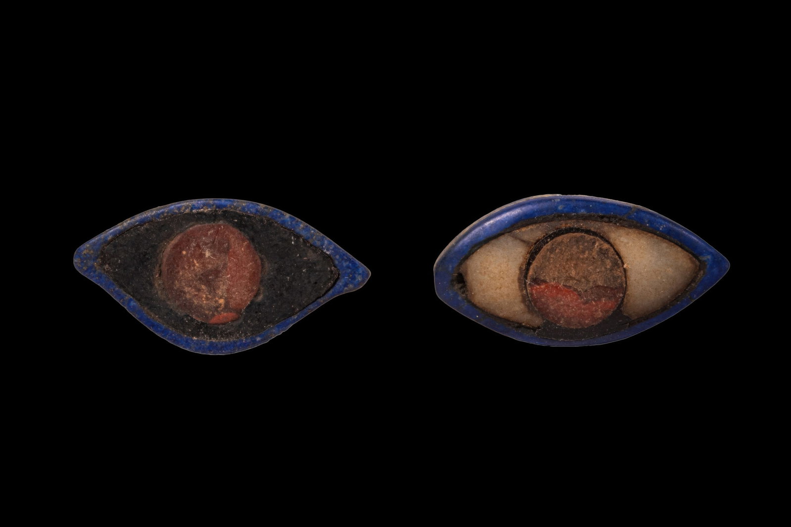 PAIR OF MESOPOTAMIAN STONE AND LAPIS LAZULI EYES: Ca. 2200 - 1800 BC. A pair of eye inlays, each carved as an almond-shaped lapis lazuli frame fitted with an opaque white sclera centred by a dark circular inlay for the iris. Size: 42-43mm x 21-22mm; 