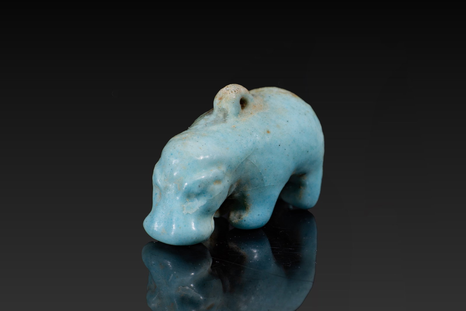 EGYPTIAN FAIENCE HIPPOPOTAMUS AMULET: Late Period, Ca. 664 - 332 BC. A blue faience amulet of a hippopotamus with a heavy rounded body, short legs and a lowered head with a broad muzzle. A suspension loop is set on the back. Size: 20mm x 