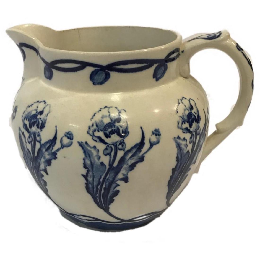 Antique Buffalo China Triumph Pitcher: BUFFALO POTTERY BLUE AND WHITE PITCHER, having a blue floral designs in the "Triumph" pattern as noted on base, on sides of low, bellied forms. Marked "SEMI-VITREOUS / BUFFALO POTTERY / TRIUMPH." This