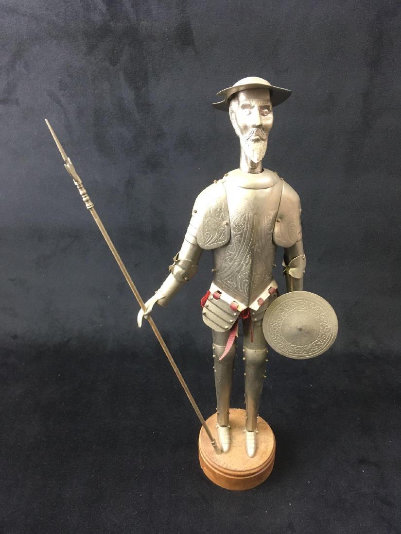 Vintage Metal Don Quixote Figurine: Vintage Metal Don Quixote Figurine; He's displayed on a round wooden pedestal and has cloth clothing underneath metal armor. It measures at approximately 1" L x 7" W x 13" H.Â