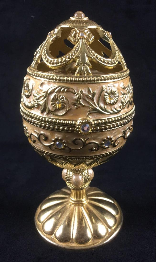Gold Pedestal Musical Box Egg: Gold Pedestal Musical Egg with Revolving Gift Box Inside. This piece is in good condition. There are some scratches and speckles from wear on the metal. The music box is functional. The exterior featu
