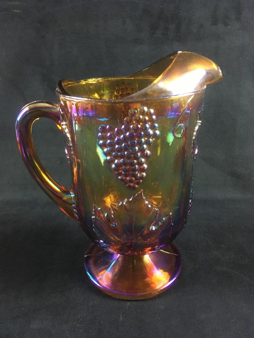 Large Vintage Carnival Glass Water Pitcher: Large Vintage Carnival Glass Water Pitcher; this shows a very strong gold and purple iridescence. The piece shows a grape and leaf motif, it is in very good condition with no chips or cracks noted. Th