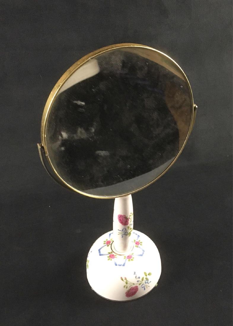 Vintage Ceramic and Brass Mounted Make-up or Shaving: Vintage Ceramic and Brass Mounted Make-up, Shaving Mirror; the handle lifts out of the base to junction as a hand mirror. The ceramic base and mirror handle show a floral motif. The base holds a music