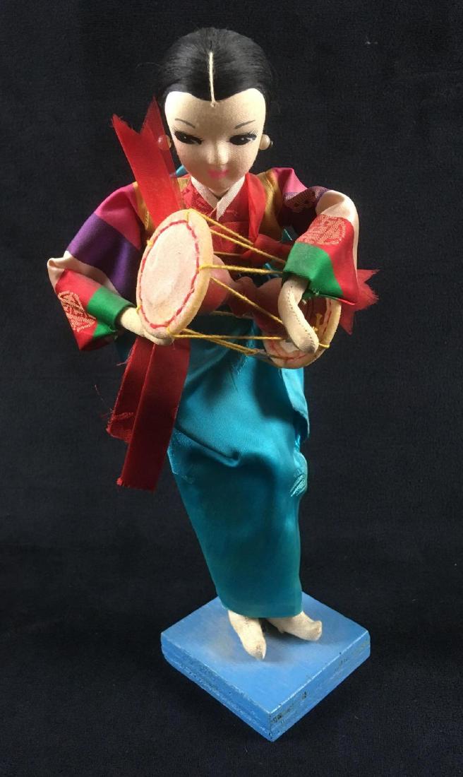 Doll in Traditional Korean Dress: Doll in Traditional Korean Dress. This doll is in fair condition. Doll is holding a traditional Korean instrument. Some dust on the doll. Body is made of fabric and wire. Doll measures 9" H and stands