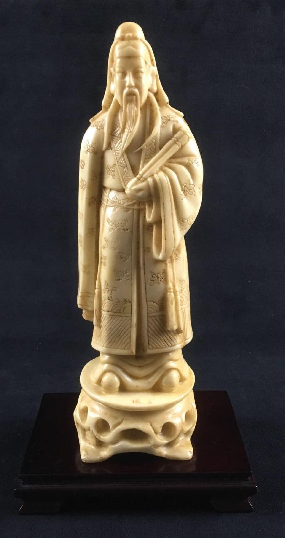 Chinese Resin Carved Man Holding Scroll Figurine: Chinese Resin Carved Man Holding Scroll Figurine. This figurine is in great condition. It features a detailed carved floral pattern on the figures robe. The statuette measures 11.5" approximately. Has