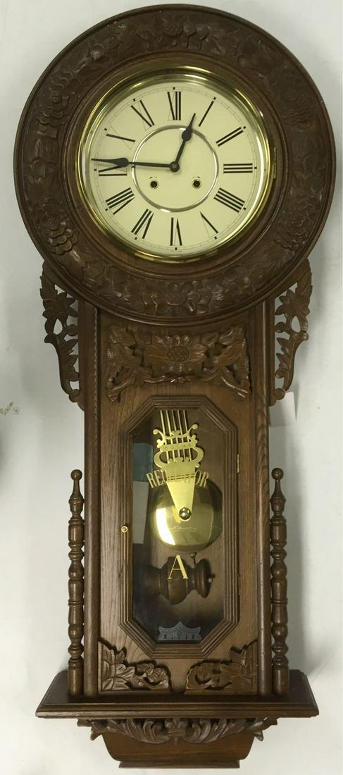 Large Regulator "A" Wall Clock Reproduction: Large Regulator "A" Wall Clock, Reproduction; this is a large reproduction of an original ornate Regulator. It shows carved oak face frame and carved detail on the pendulum box. The clockwork is windu