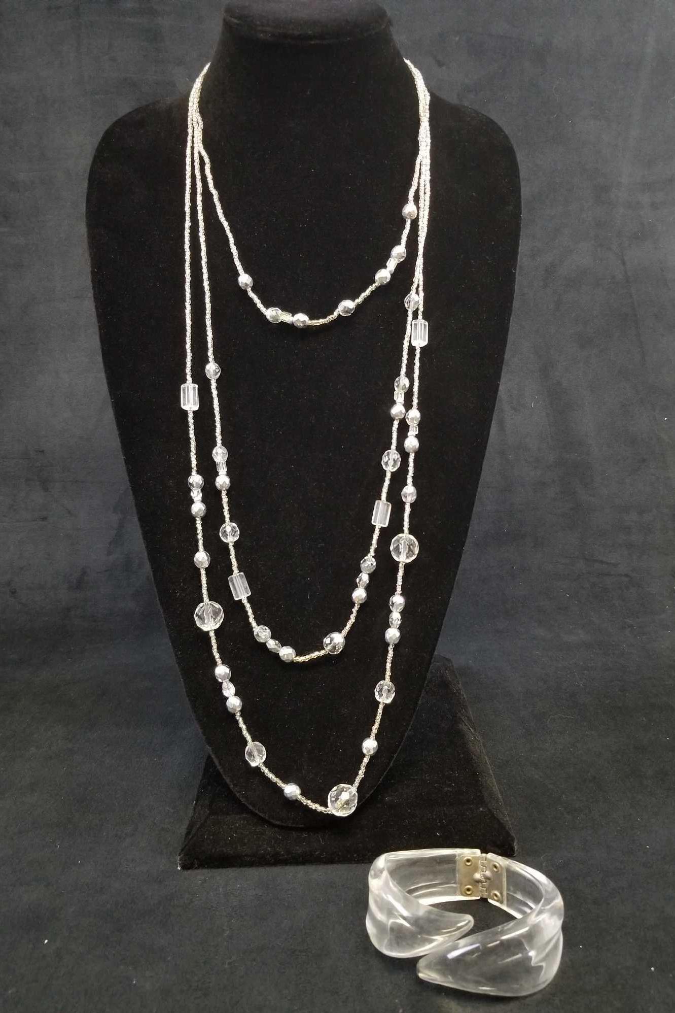 3 Layered Clear Beaded Necklace with Clear Acrylic Cuff: This jewelry set includes a 3 layered beaded necklace with the longest chain measuring at about 29" and the shortest measuring 20". It is in good used condition with no known damages. The Acrylic brac