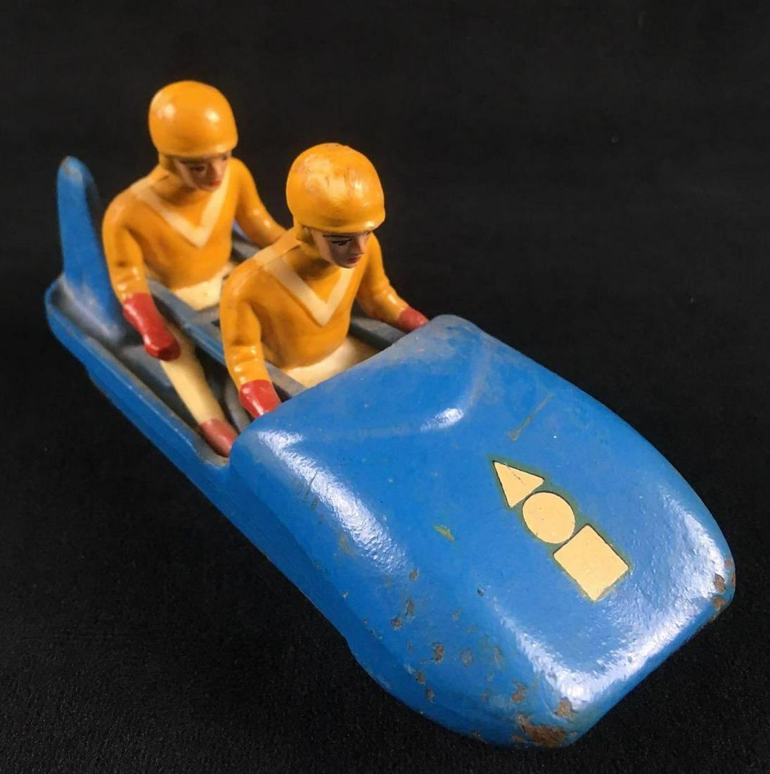 Hela Bob Two Man Bobsled from Germany: Cast Iron Two Man Sled from Germany, made by Hela-Bob, designed by Karl Heusser. This toy is in good condition overall. The paint has some light wear, and there is some paint loss on the front and bot