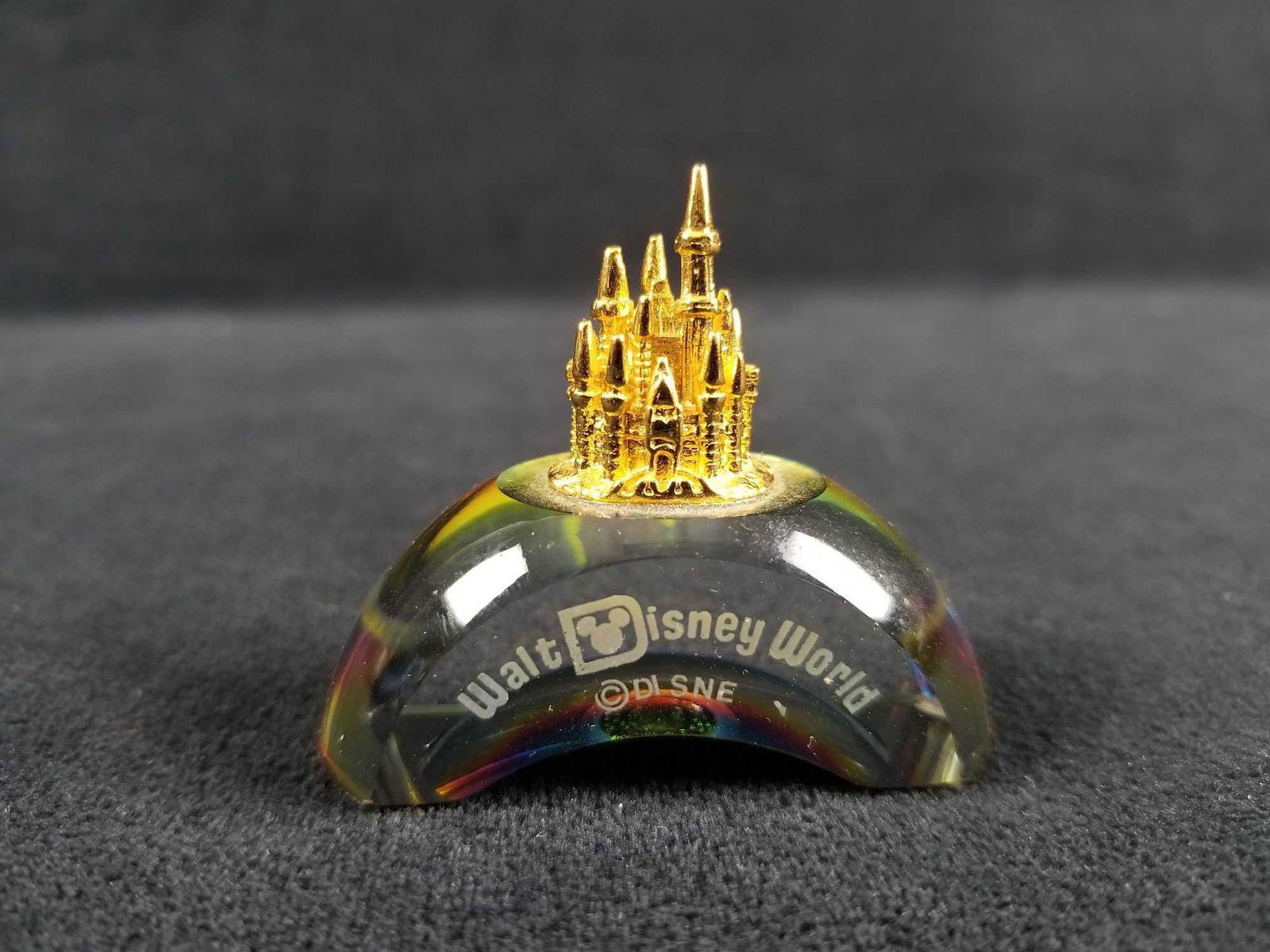Cinderellas Castle Walt Disney Glass Figurine: This here is a gold toned Cinderella's Castle on a rainbow reflective glass that has the words Walt Disney World displayed on the front. The letter "Y" is missing as it might have been smudged off. Ot