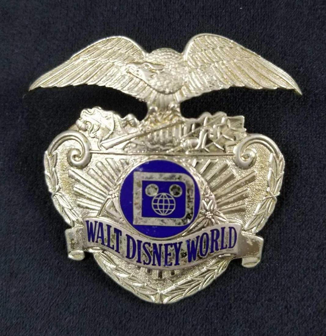 Vintage Early 1970s Disney Security Badge A: Walt Disney World Security Hat Badge with Original Hardware.Â This badge adorned the hat of the Walt Disney World Park Security Employees. The back of the badge has two threaded prongs that fit thro