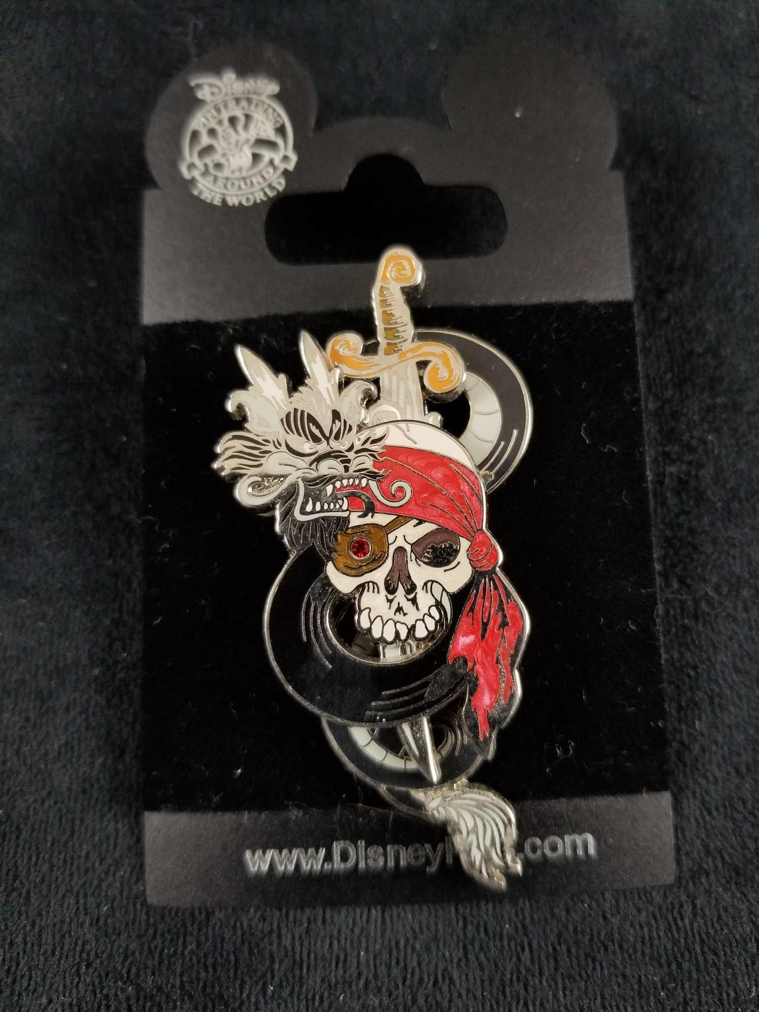 Pirates of the Caribbean Disney Pirate Skull With: Pirates of the Caribbean pin with sliding feature. Sword can be pulled up to reveal "Pirates of the Caribbean" Logo. Pin comes with backing card and measures approx 1" x 3". Is in good condition with 