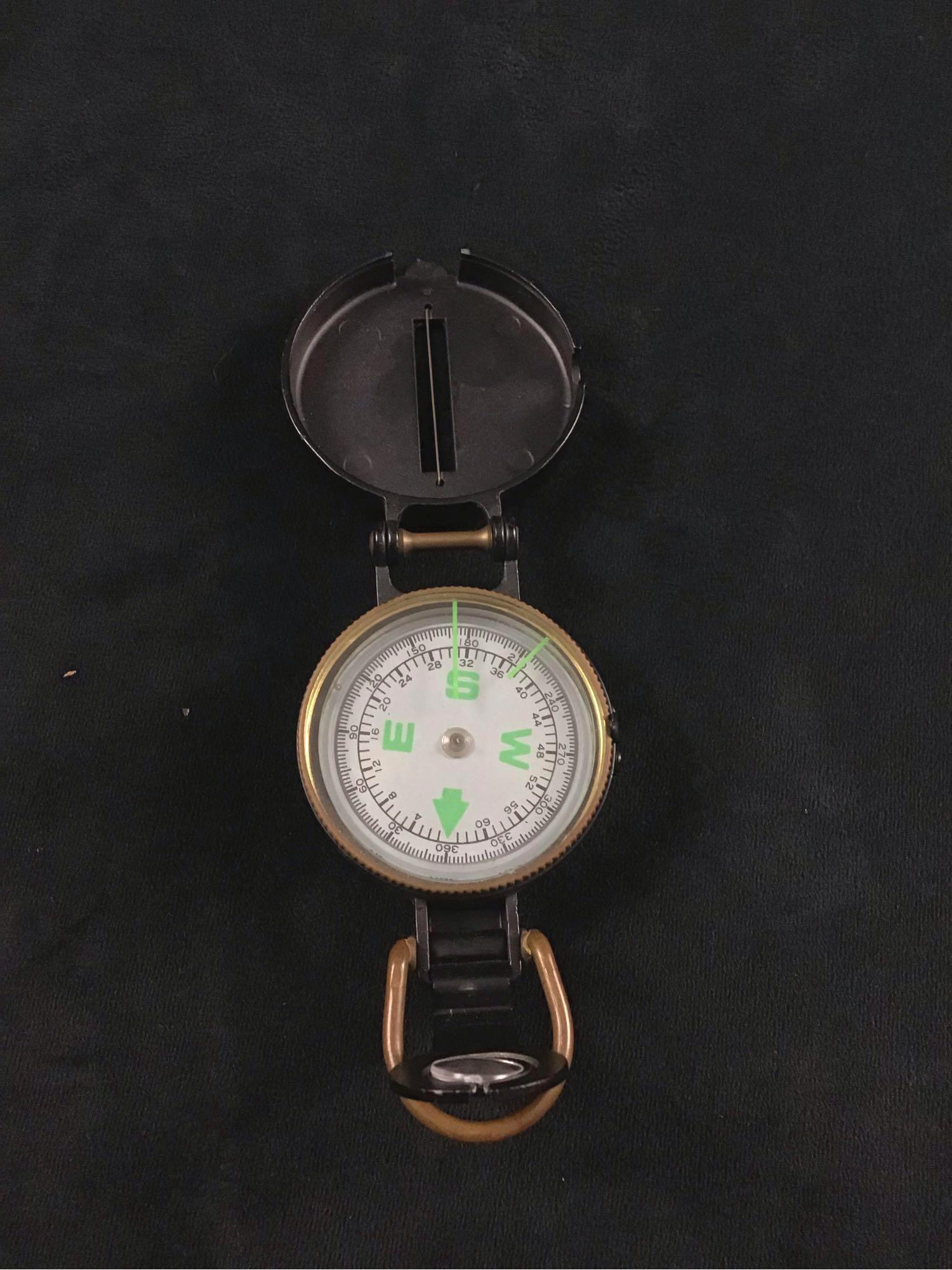 Modern Engineer Directional Compass: This is a modern compass with "Engineer directional compass" written on the top cover. The outer casing is made of hard metal colored black. The North, East, West and South symbols are green. The numb