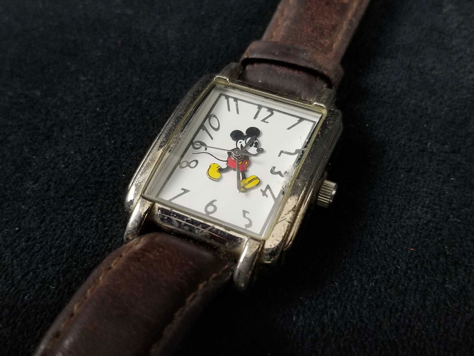 Disney Mickey Mouse Stainless Steel With Leather Band: Stainless steel watch with an image of a walking, cheerful Mickey Mouse by "Disney Time Works". There is heavy wear on the leather band and case. The battery is untested. The bezel is clear and has no