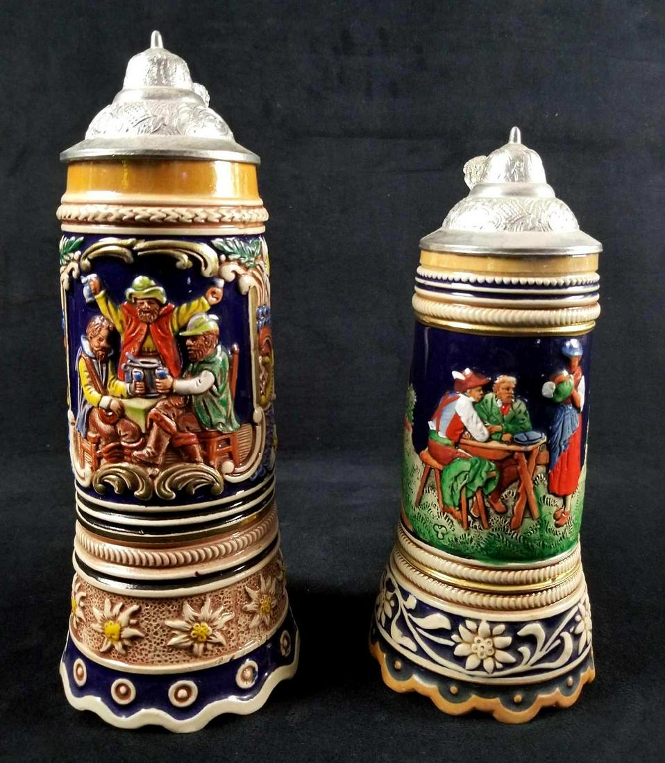 Lot of 2 German Musical Beer Steins with Beautiful: This lot of 2 German Musical Beer Steins with Lid and beautiful details are in great used condition with no known damages. The stein on the left features 3 men drinking at a table and inscribed is Ein