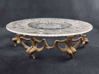 Vintage Centerpiece Glass Platter W Brass Cherubs: Vintage glass platter with an interesting brass circle stand of cherubs that hold the glass plater. Platter has an unique sun and floral design. Is approx 13" x 13" x 3". Glass is in good, vintage
