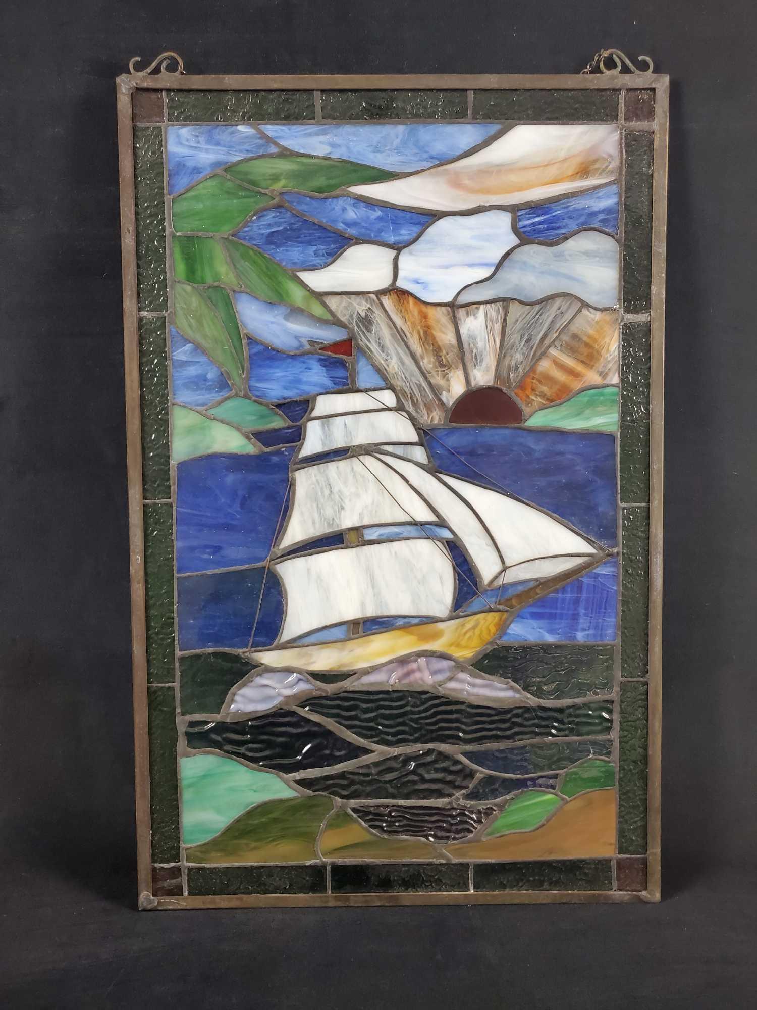 Tiffany Style Hanging Stained Glass Sailing Ship: Tiffany style hanging stained glass of a ship sailing towards land as the sun sets.Colorful glass looks even better with light behind it. Glass is in good, used condition with no known damage. Is appr