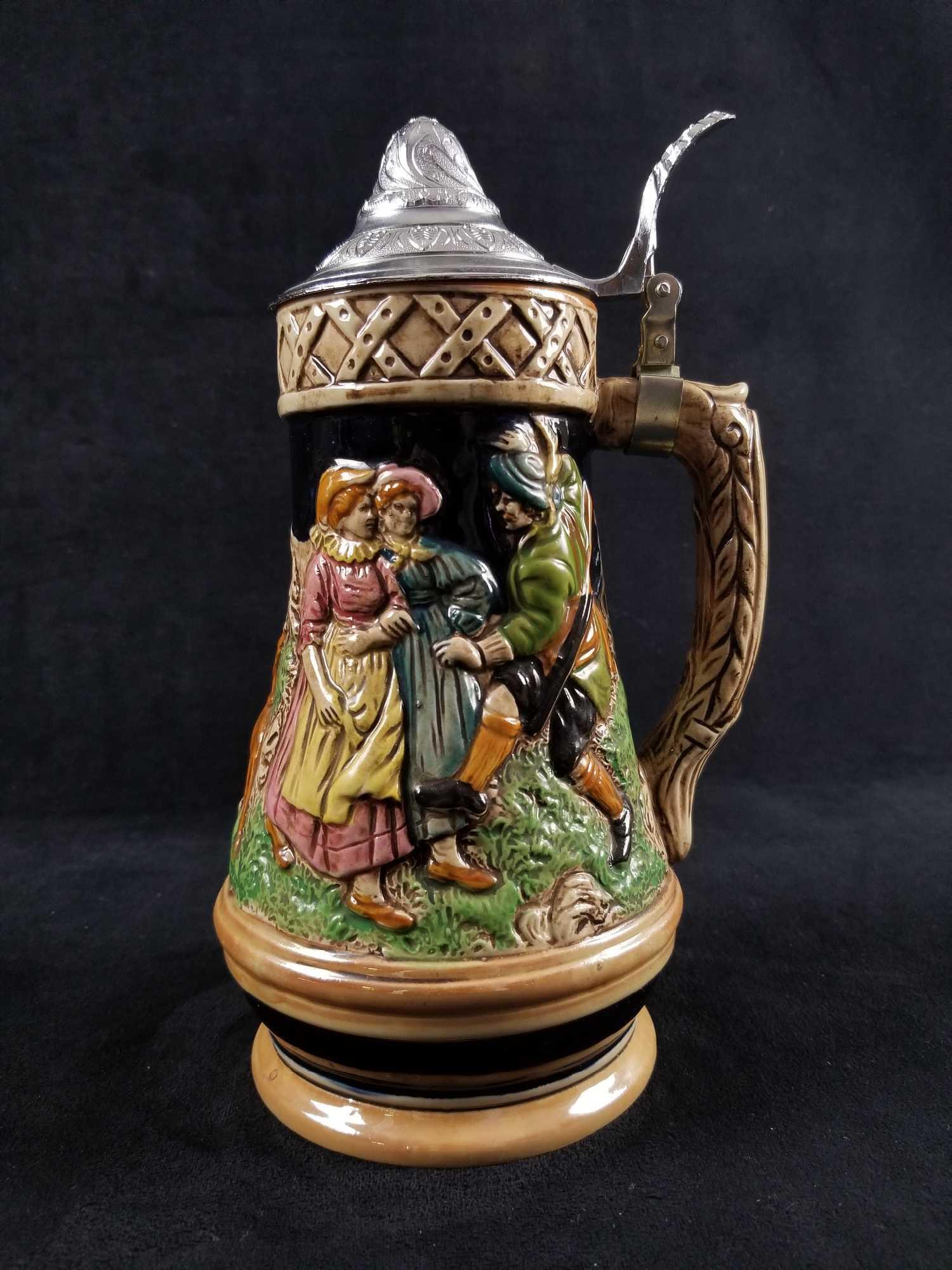 German Musical Beer Stein with 3 Dancing People and 3: This German musical beer stein with pewter lid features 2 woman and a man who appears to be dancing in a grassy field along side 3 dogs. Features a Swiss musical instrument but unfortunately I was una